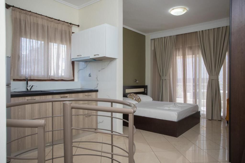 A hotel room with a bed, a small kitchenette, and a view of the city.