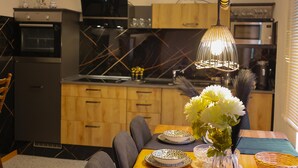 Une cuisine moderne avec des meubles en bois, un plan de travail noir et un coin repas avec une table dressée pour deux personnes.
