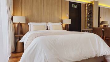 Une chambre d’hôtel avec un grand lit, deux lampes de chevet, un minibar et une porte portant l’inscription « SORTIE ».