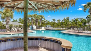 A swimming pool with a wooden pergola overhead, surrounded by palm trees and lounge chairs. - Book Coastal Cottage – Short Drive to the Beach! (Gulf Shores)