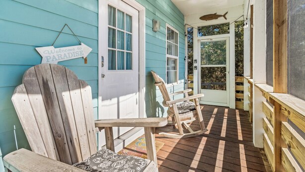 A wooden deck with rocking chairs and a sign that reads "Welcome to Paradise." - Book Coastal Cottage – Short Drive to the Beach! (Gulf Shores)