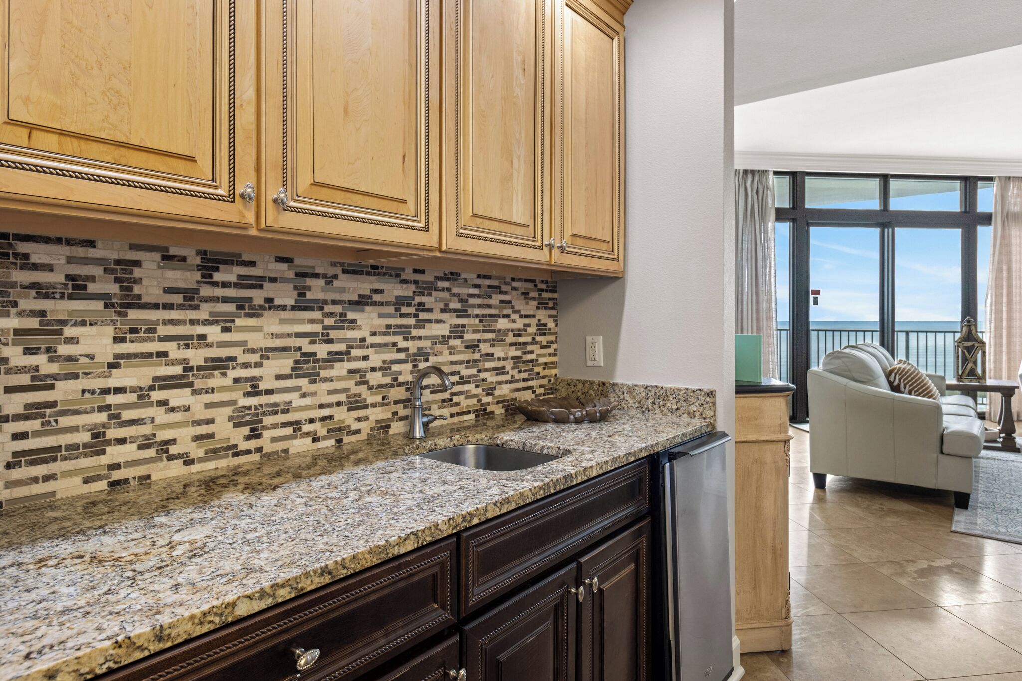 A kitchen with wooden cabinets, a tiled backsplash, granite countertops, and a built-in sink.