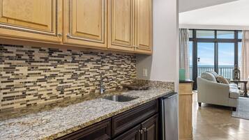 A kitchen with wooden cabinets, a tiled backsplash, granite countertops, and a built-in sink.