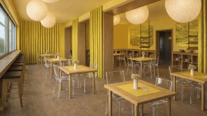 Un restaurante moderno con sillas transparentes, mesas de madera e iluminación colgante esférica.