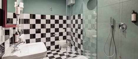 Un bagno con pavimento a scacchi, cabina doccia in vetro, lavandino e WC.