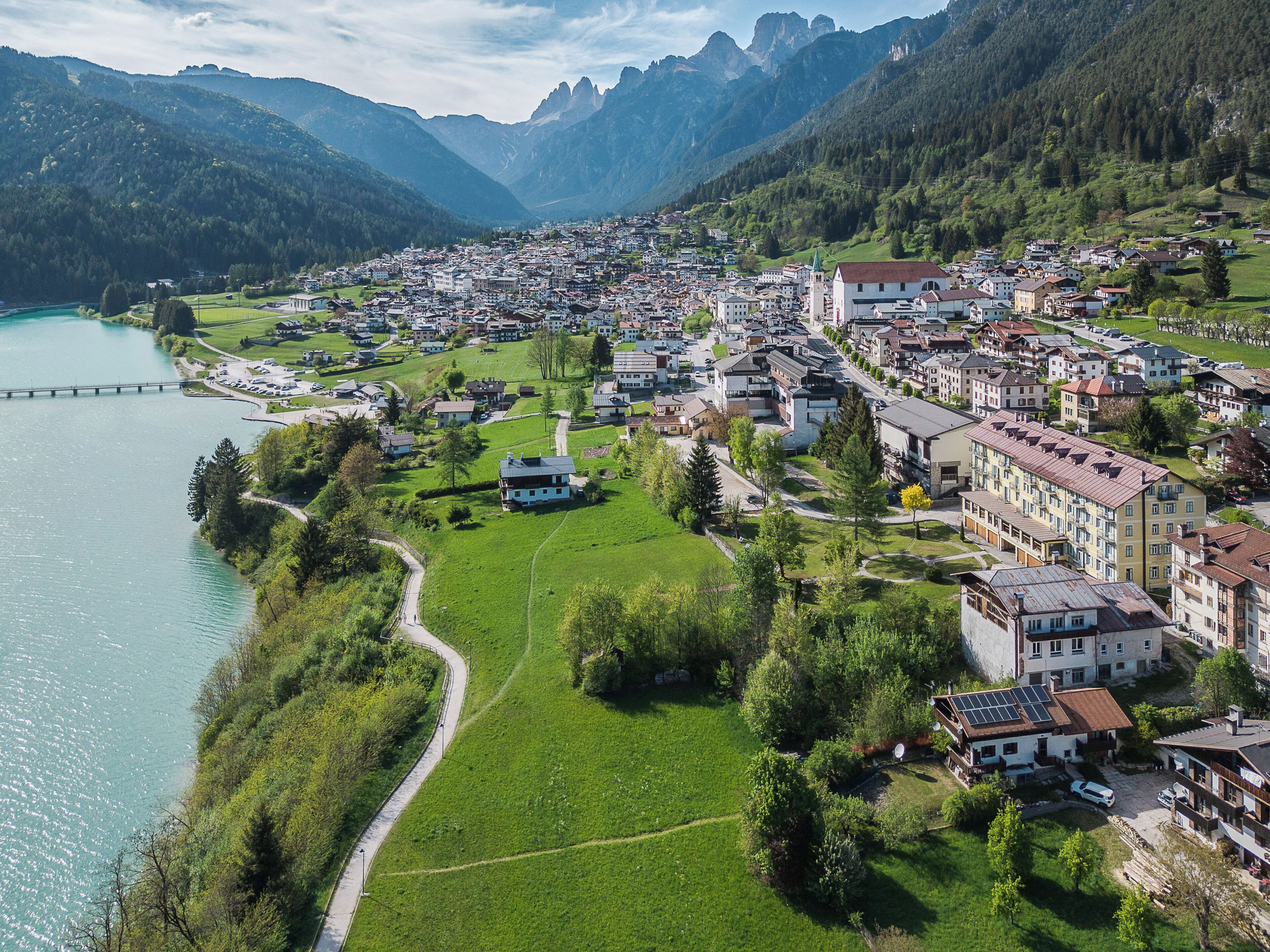 Un pueblo con un río, colinas verdes y un puente.