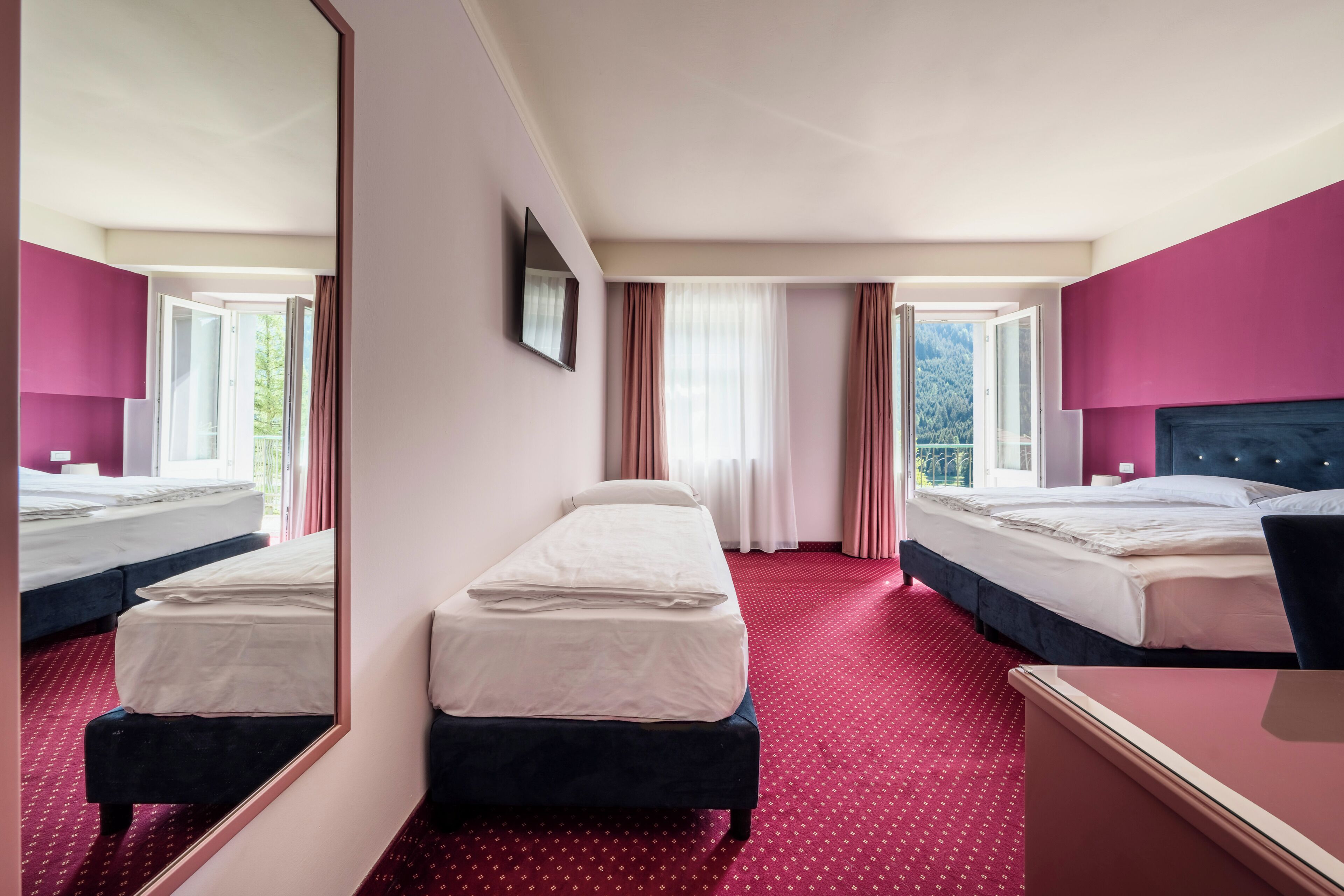 Habitación de hotel con dos camas, un espejo grande y vistas al exterior.