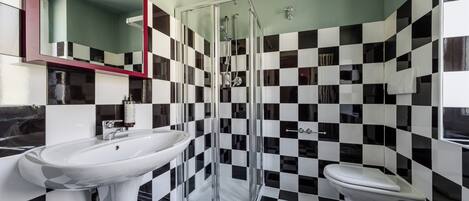 Un bagno con pavimento a scacchi, box doccia in vetro e lavandino bianco.
