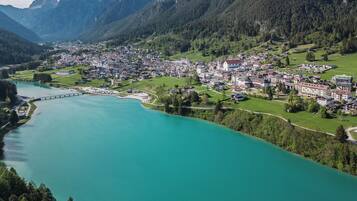 A town by a turquoise river with a bridge, surrounded by mountains.