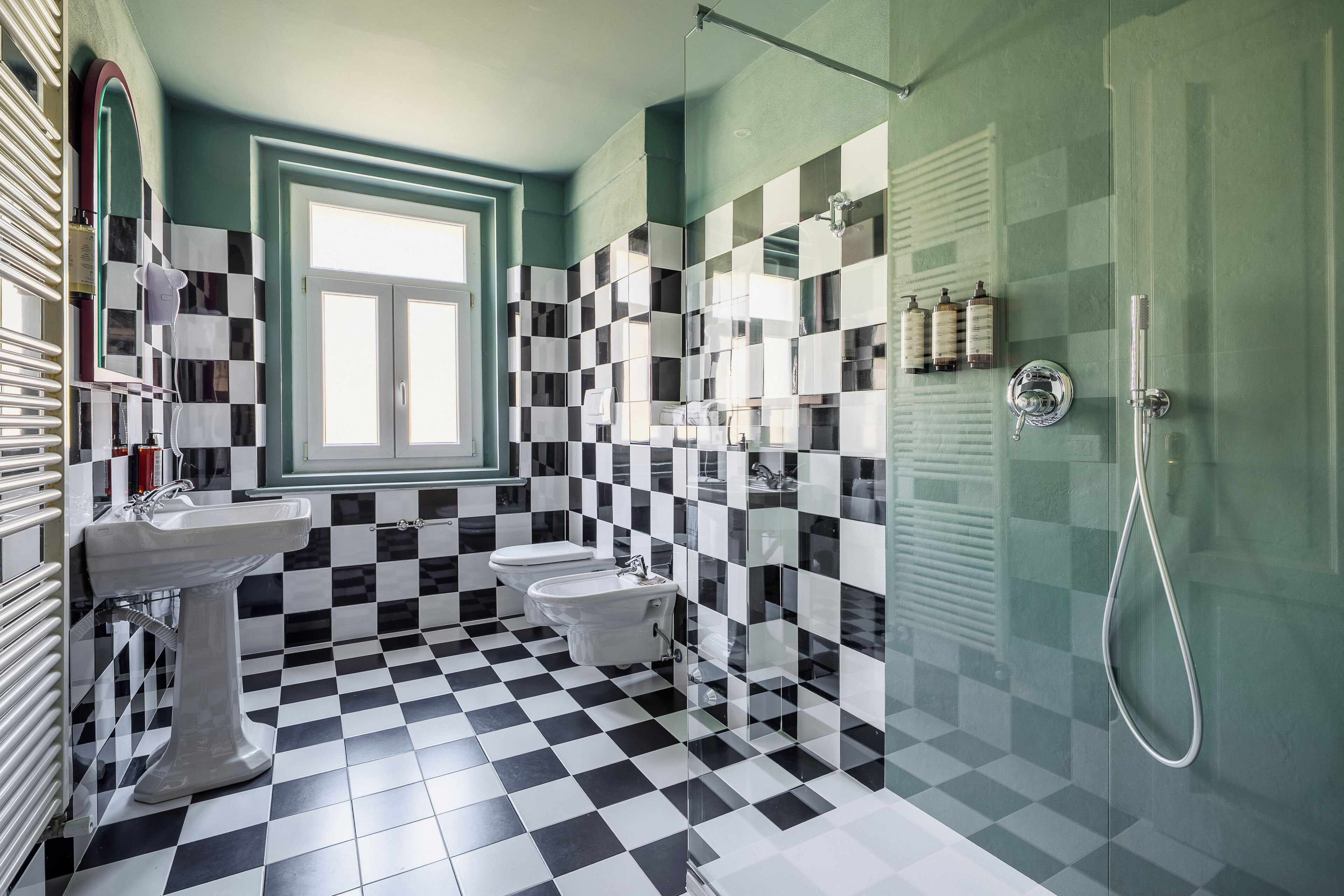 A bathroom with a checkered floor, a sink, a toilet, and a shower.