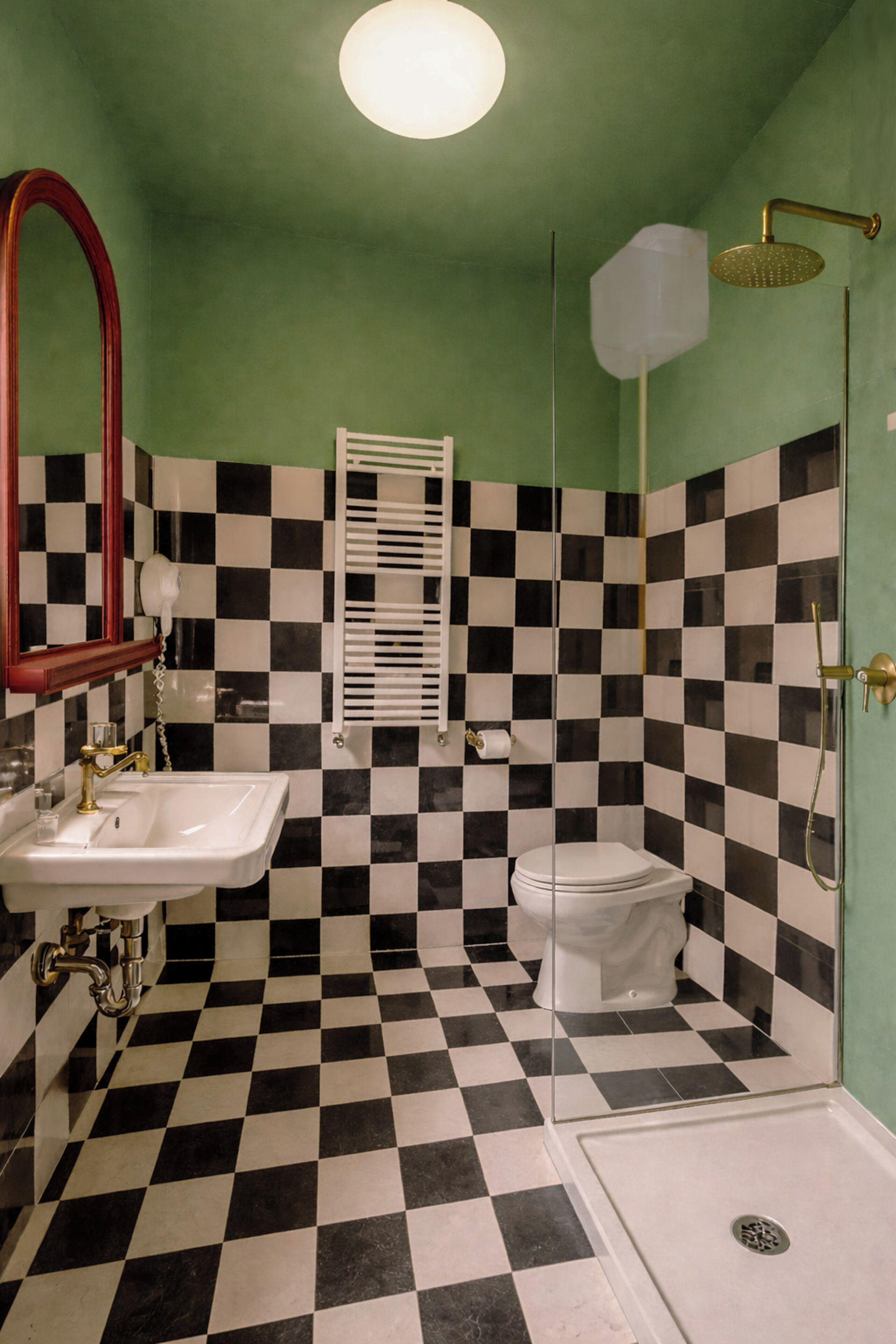 Un baño con piso a cuadros, lavamanos, inodoro y ducha.
