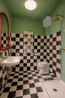 Un baño con piso a cuadros, lavamanos, inodoro y ducha.