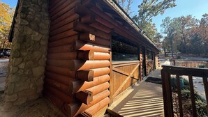 Una cabaña de madera con base de piedra, un porche y vistas a los árboles circundantes.