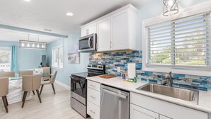 A modern kitchen with white cabinets, a stainless steel sink, and a tiled backsplash. - Blue Dolphin (Santa Rosa Beach)