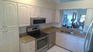 A kitchen with white cabinets, a microwave, an oven, a sink, and granite countertops.