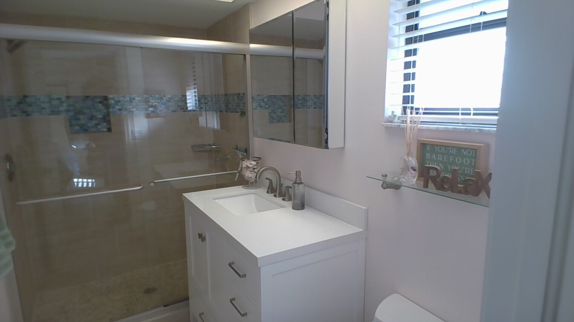 Een badkamer met douche, wastafel, spiegel en toilet.