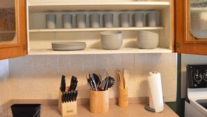 Une cuisine avec des meubles blancs, une cuisinière et divers ustensiles.