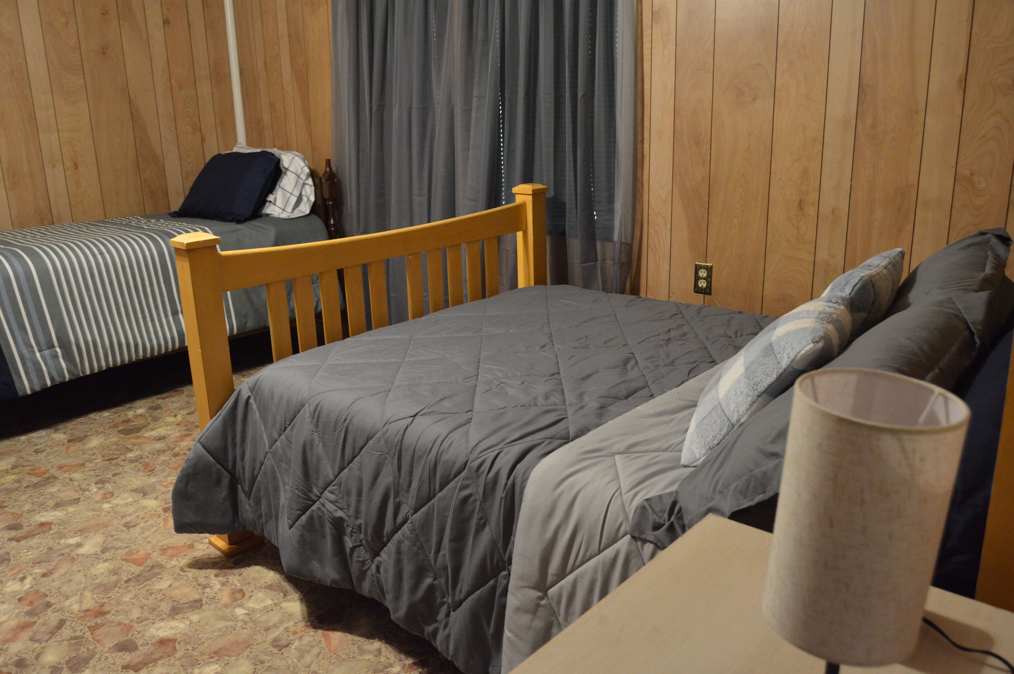A room with a bed, a wooden headboard, a bedside table, and a lamp.