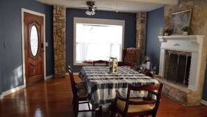 Une salle à manger avec une table dressée pour quatre personnes, une cheminée et un mur d’accent en pierre.