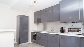A modern kitchen with grey cabinets, a stainless steel refrigerator, a built-in oven, a microwave, and a sink. - 05 -b902 in Portim o (Portimão)