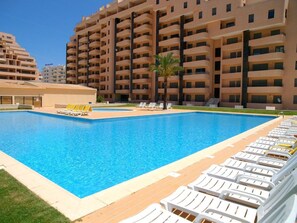 A swimming pool with lounge chairs and a building with multiple balconies in the background. - 05 -b902 in Portim o (Portimão)