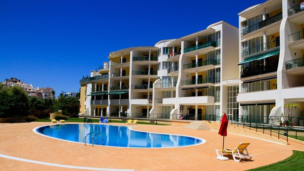 Ein modernes Hotel mit Schwimmbad, mehreren Balkonen und einer gepflegten Rasenfläche.