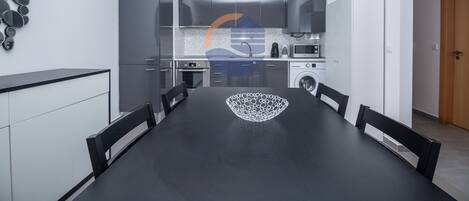 A modern kitchen with grey cabinets, a built-in oven, microwave, and washing machine.