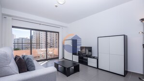 A modern living room with a sofa, a TV, and a balcony with a view of buildings. - 08 - B600 in Portim o (Portimão)