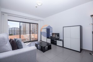 A modern living room with a sofa, a TV, and a balcony with a view of buildings. - 08 - B600 in Portim o (Portimão)