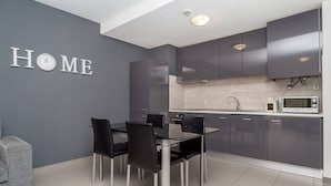 Una cocina moderna con armarios grises, una mesa de comedor de vidrio y un sofá gris.