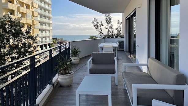 A balcony with a dining table and chairs, a sofa, and potted plants. - 43 (Portimão)