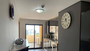 Una cocina moderna con horno empotrado, microondas y lavaplatos. Una ventana grande ofrece vistas al exterior.