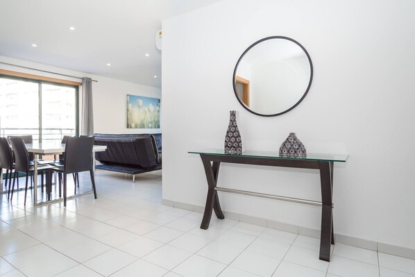 A modern dining area with a glass-top table, dark metal frame, and two patterned vases.
