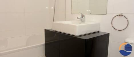 A modern bathroom with a white sink, black vanity, and a mirror above the sink.