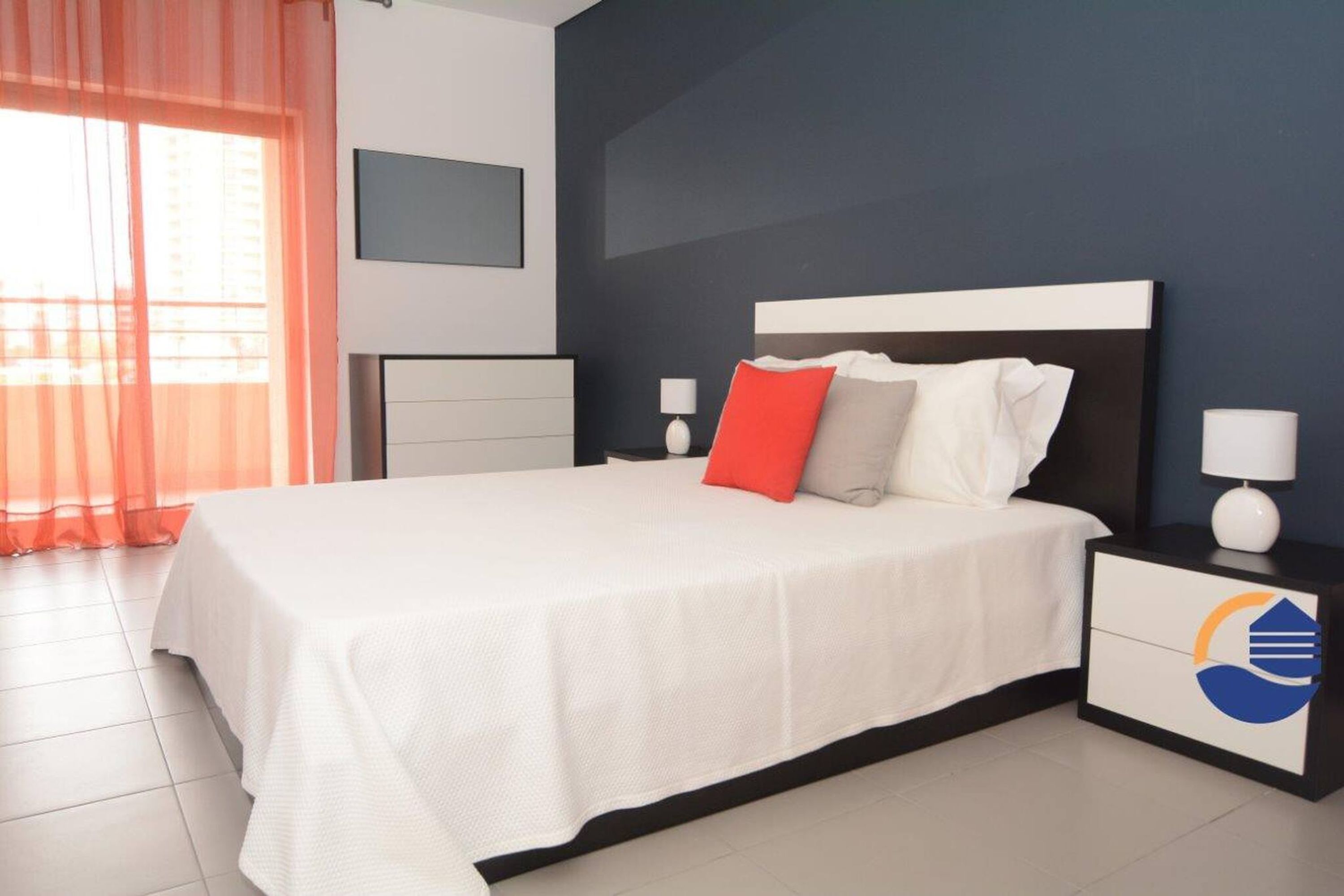 Une chambre moderne avec un grand lit, une table de chevet avec une lampe et un téléviseur fixé au mur.
