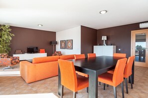 A modern living room with a dining area, featuring a sofa, chairs, a table, and a TV. - 23 (Portimão)