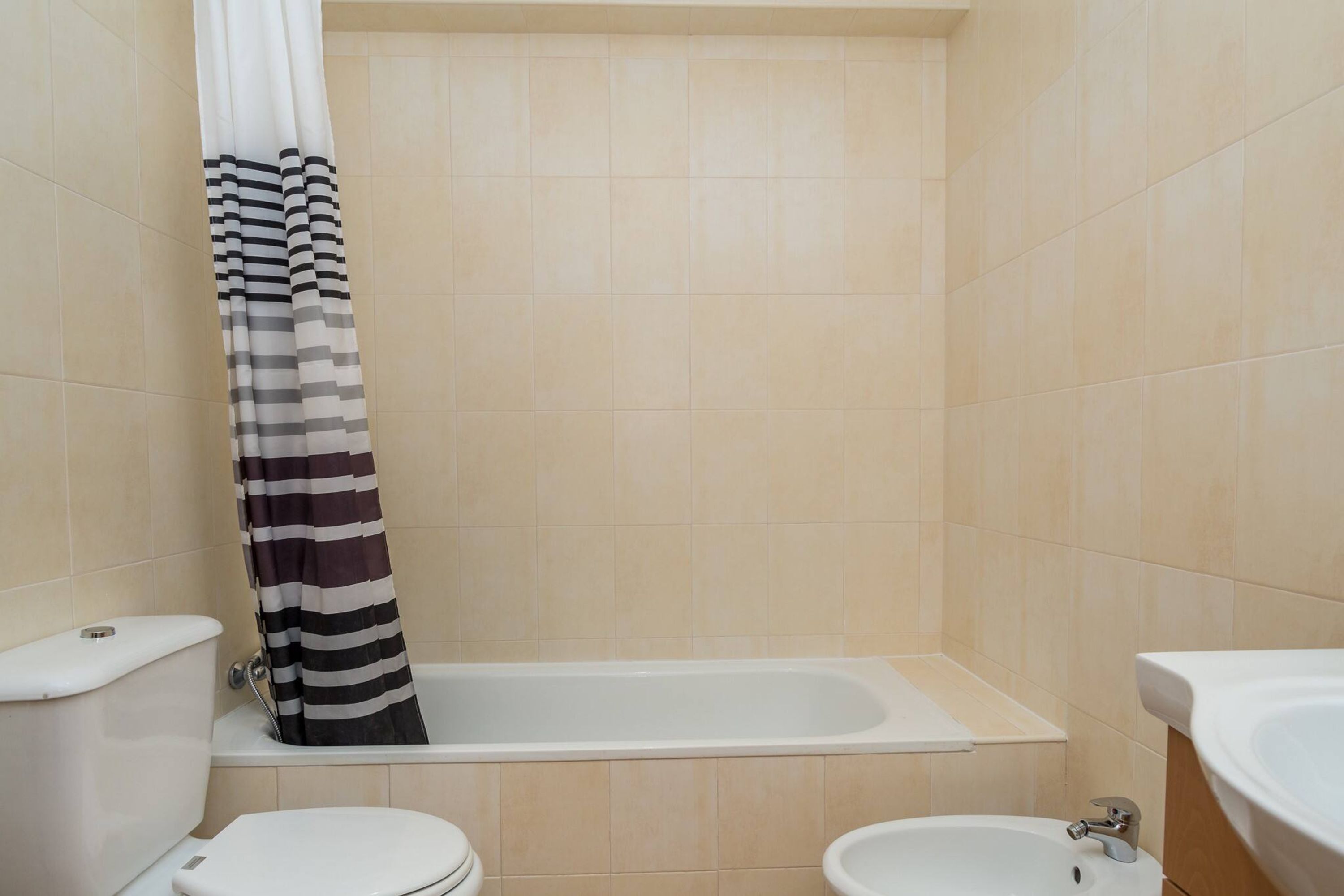 A bathroom with a bathtub, toilet, and bidet.
