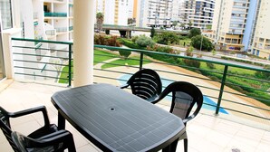 A balcony with a table and chairs, overlooking a residential area with high-rise buildings and a green park. - 41 (Portimão)