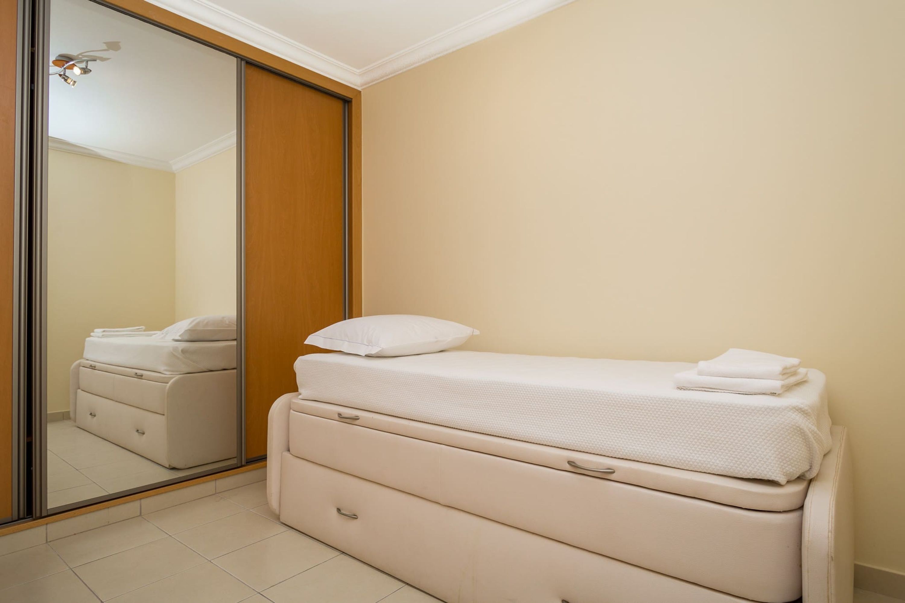 Une chambre à coucher avec un lit, un miroir et une armoire.