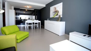 A modern living room with a green sofa, a white dining table, and a kitchen in the background. - 09 - B707 in Portim o (Portimão)