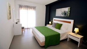 A modern hotel room with a large bed, a bedside table with a lamp, a desk with a chair, and a window with curtains. - 09 - B707 in Portim o (Portimão)