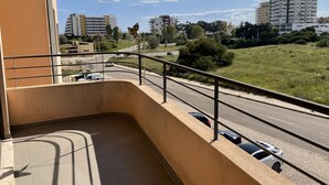 A balcony with a view of a road, buildings, and a grassy area. - 13 - B315 in Portim o (Portimão)
