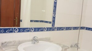 A bathroom with a white sink, a mirror, and a bathtub. - 30 (Portimão)