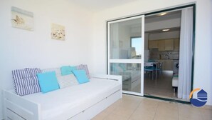 A modern living room with a white sofa, a glass door leading to a kitchen, and two wall-mounted pictures. - 30 (Portimão)