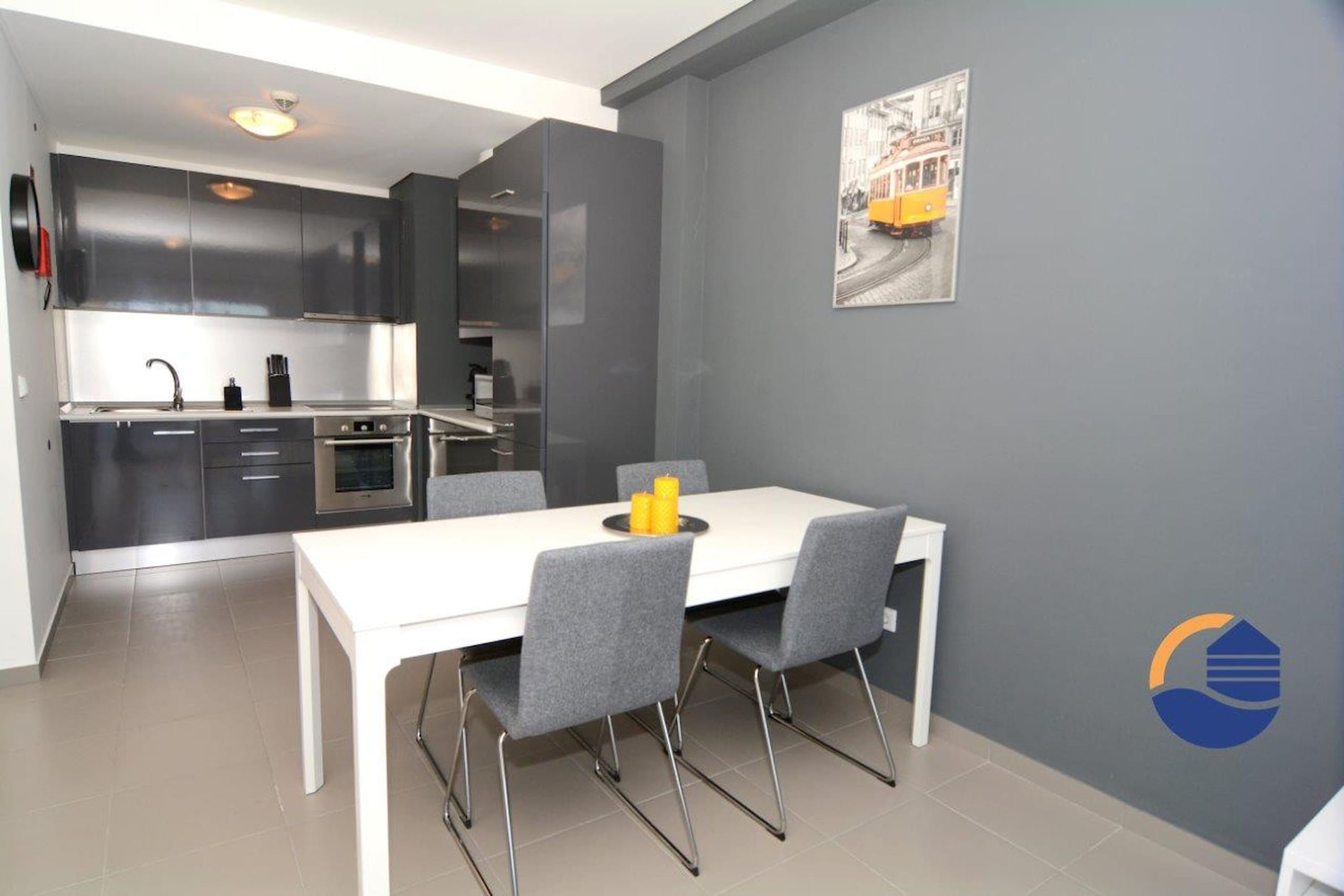 A modern kitchen with grey cabinets, a white dining table, and a grey chair.