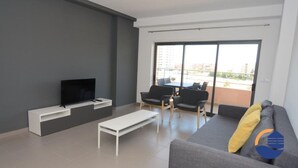 A modern living room with a flat-screen TV, a sofa, a coffee table, and a balcony with a table and chairs. - 16 - B709 in Portim o (Portimão)