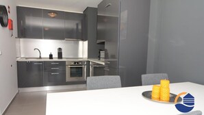 A modern kitchen with grey cabinets, a white countertop, and a dining table with two chairs. - 16 - B709 in Portim o (Portimão)