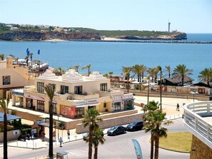 Vista costera con un edificio que tiene un restaurante llamado 'Havaianas' y un puerto deportivo.