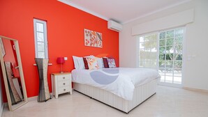 A bedroom with a bed, a nightstand, a mirror, and a window.