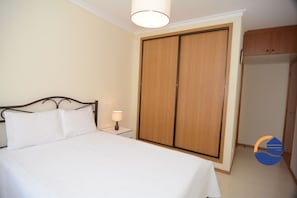 Une chambre à coucher avec un lit, une table de chevet et une armoire.